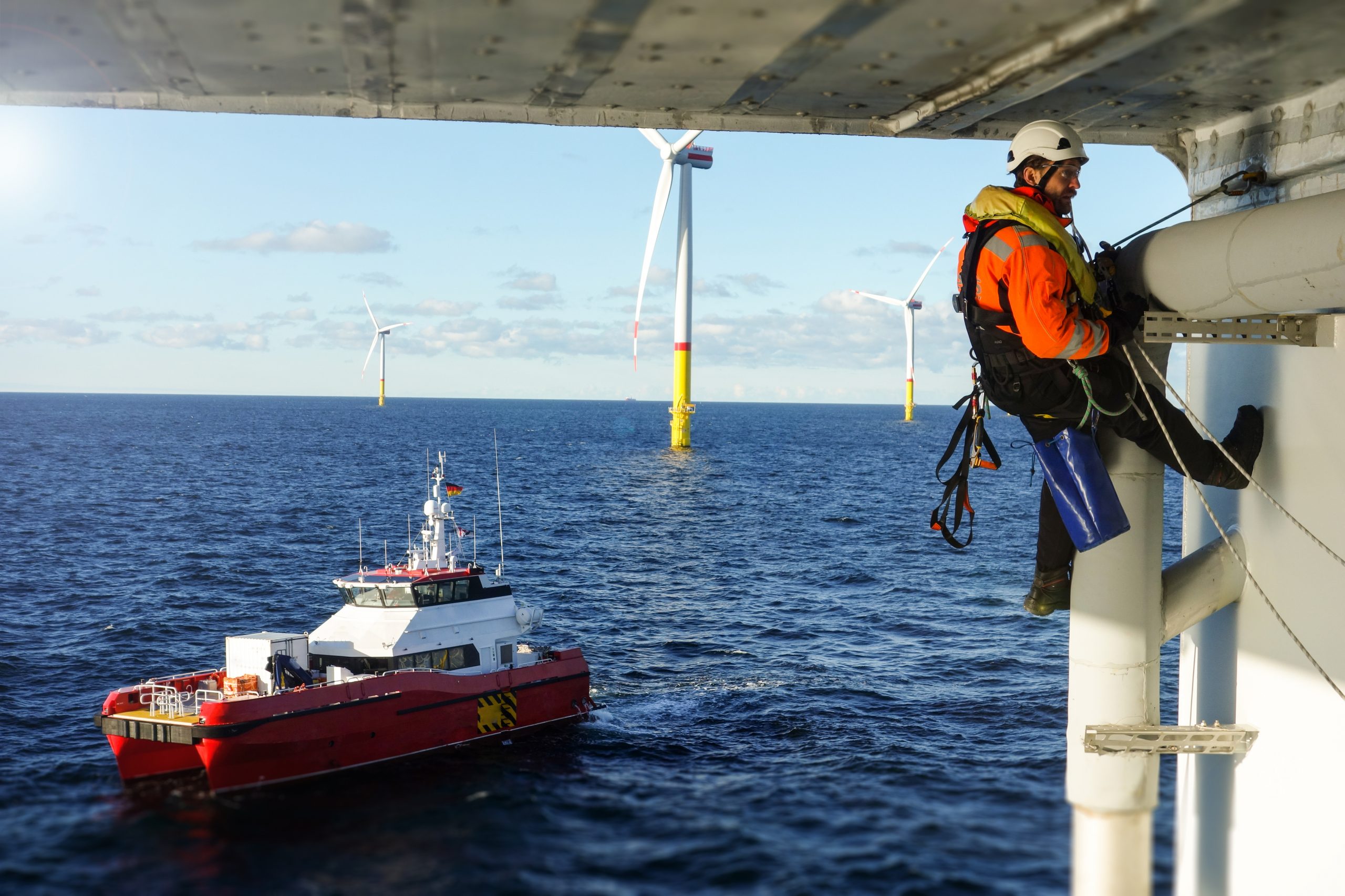 Rope access technician making inspection, repairing on offshore platform with transfer vessel guarding